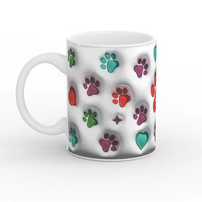 Weiße Keramiktasse mit bunten Pfotenabdrücken und Herzen, seitliche Ansicht mit Henkel auf der linken Seite.